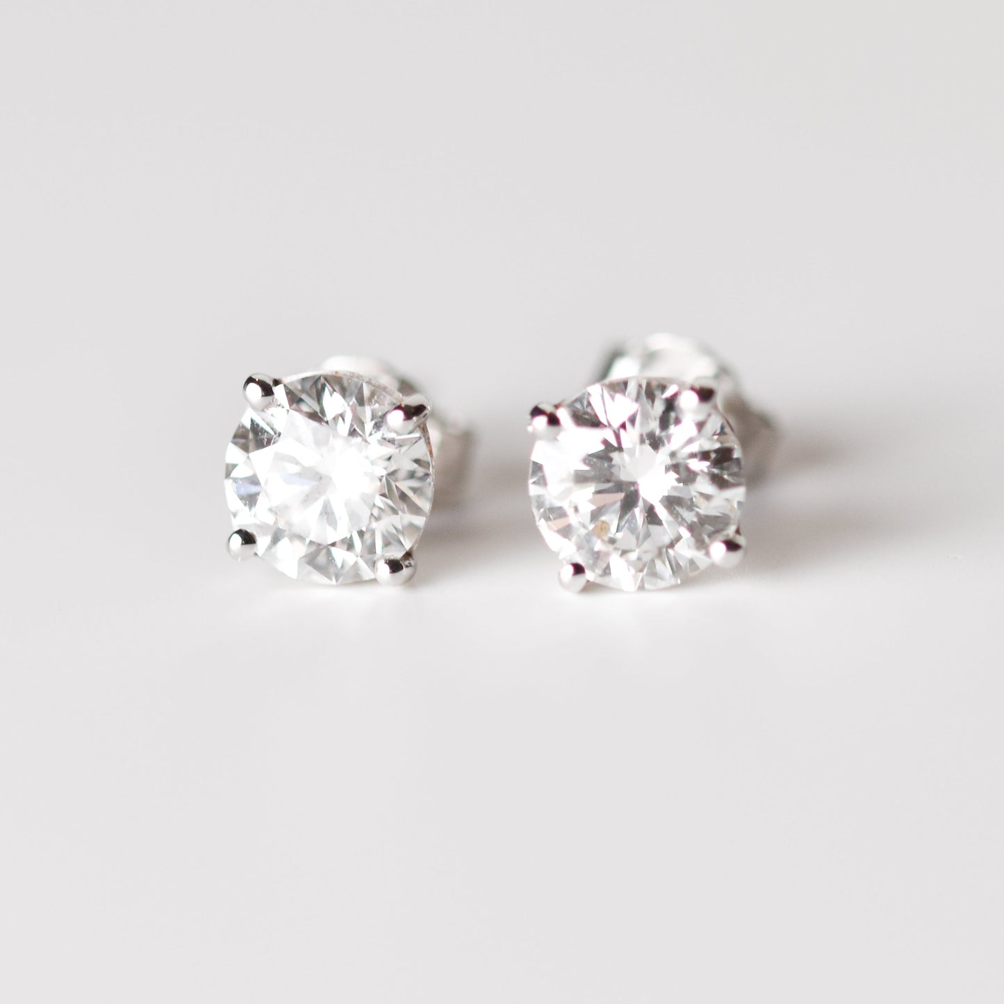 Aretes tipo stud con moissanitas en corte redondo y plata esterlina con baño de oro blanco 18K