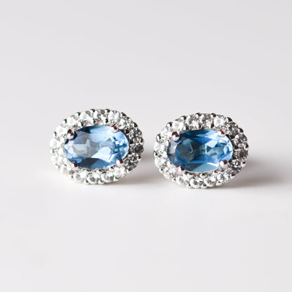 Aretes tipo stud con topacio London Blue y halo de zafiros blancos de laboratorio