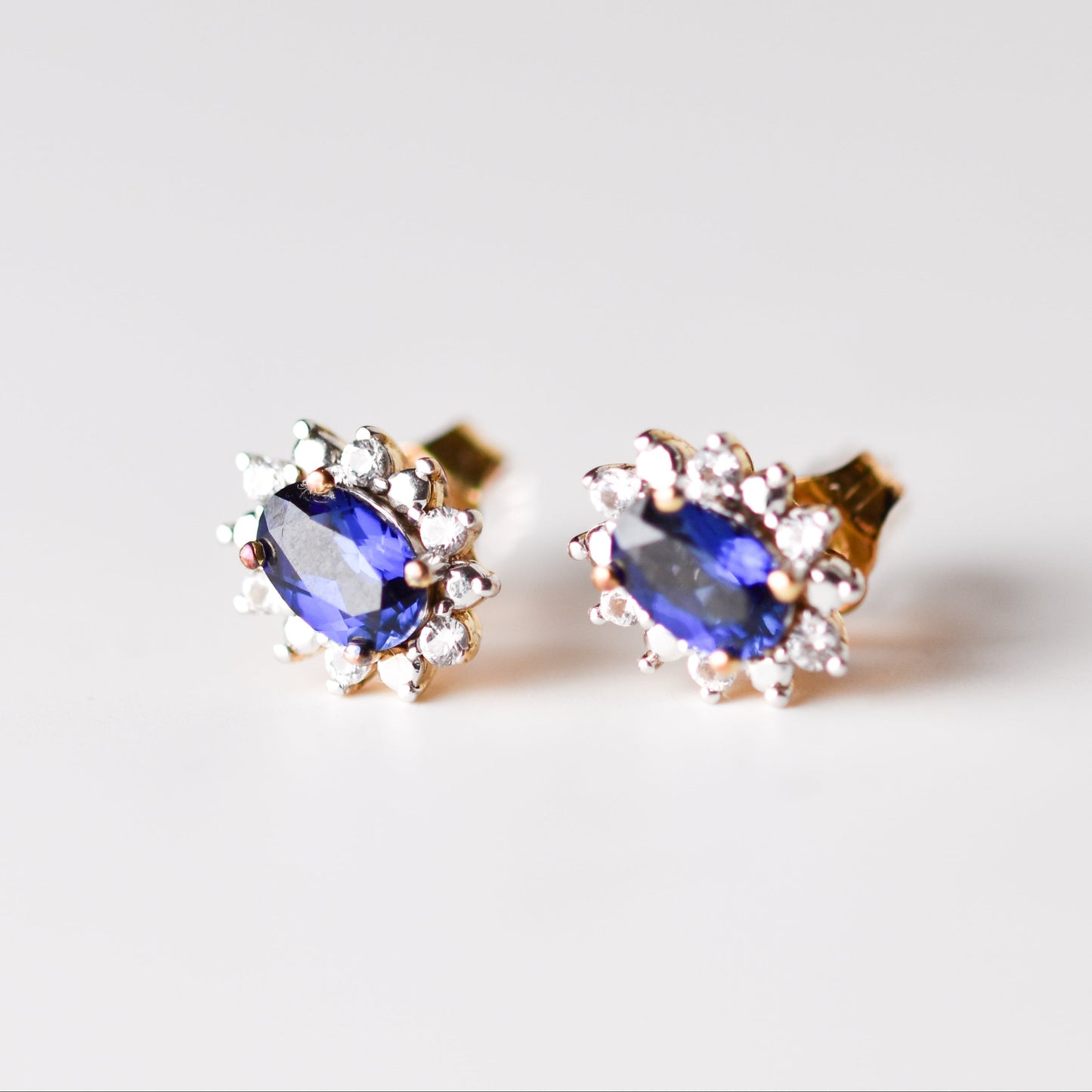 Aretes tipo stud con zafiro azul y zafiro blanco en plata con baño de oro