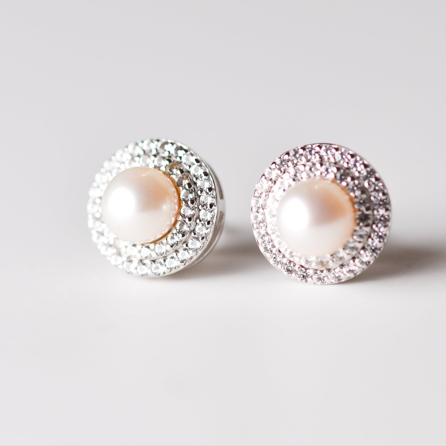 Aretes tipo stud con perla cultivada y halo de zafiros blancos creados en laboratorio