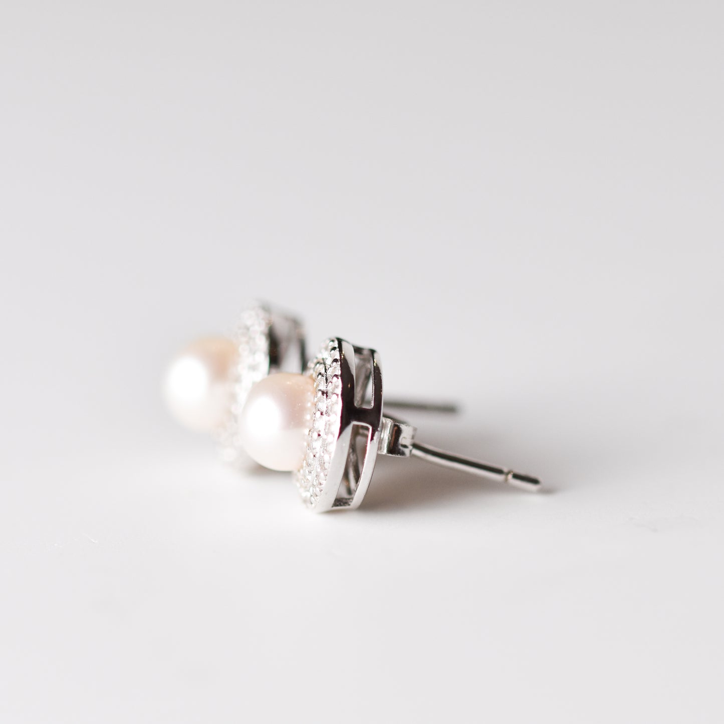 Aretes tipo stud con perla cultivada y halo de zafiros blancos creados en laboratorio