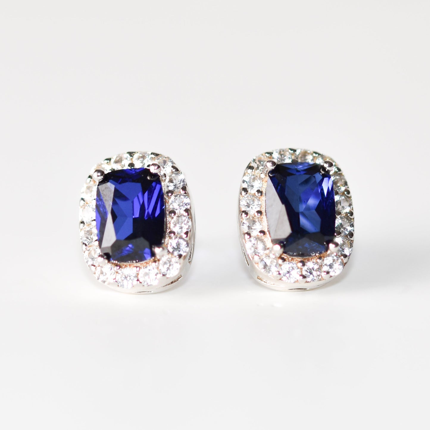 Aretes tipo stud con zafiro azul y halo de zafiros blancos creados en laboratorio