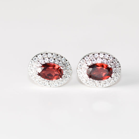 Aretes tipo stud con granate natural y halo de zafiros blancos de laboratorio