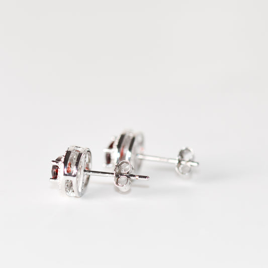 Aretes tipo stud con granate natural y halo de zafiros blancos de laboratorio