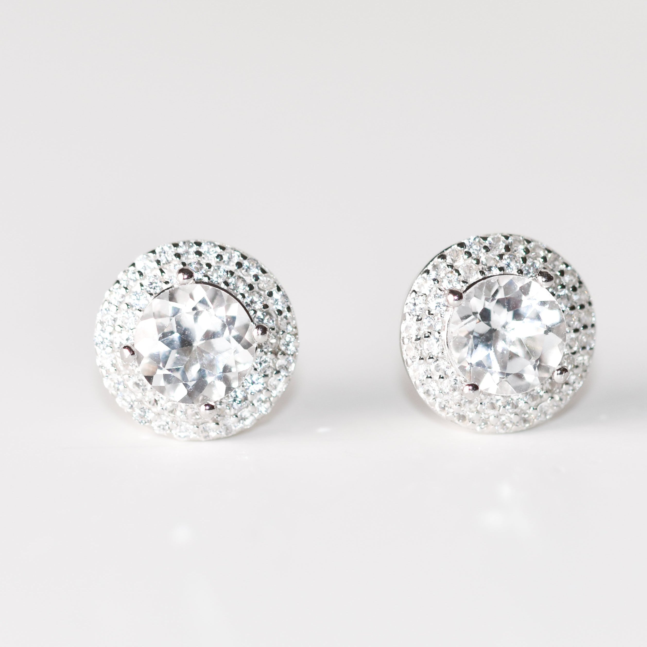 Aretes tipo stud redondos (1.5 ct) y halo de zafiros blancos