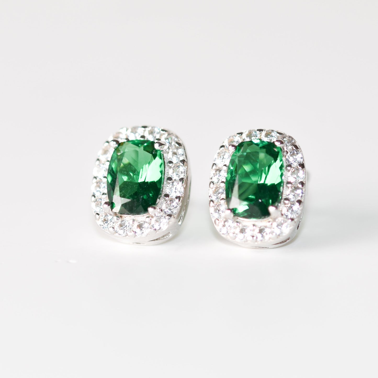 Aretes tipo stud con esmeralda y halo de zafiros blancos creados en laboratorio en plata esterlina