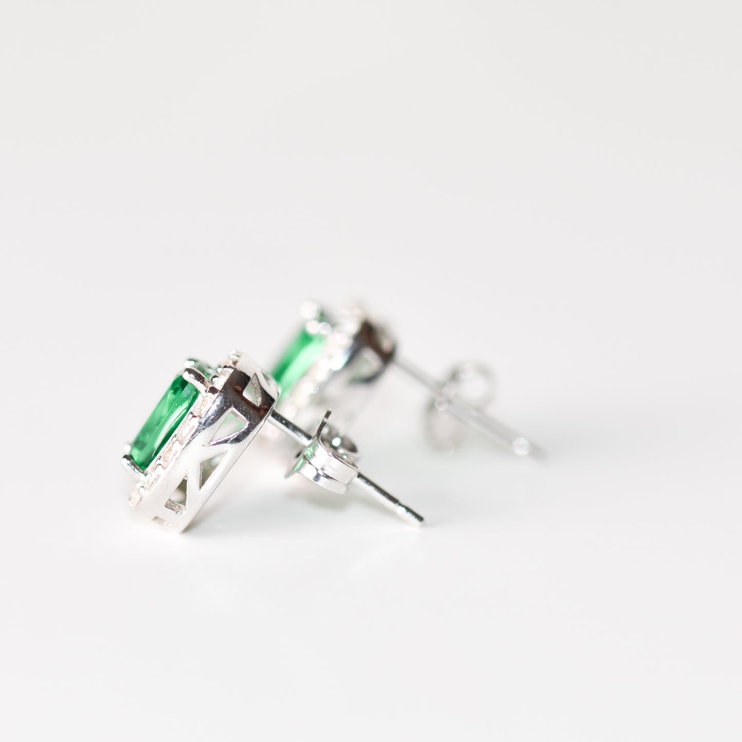 Aretes tipo stud con esmeralda y halo de zafiros blancos creados en laboratorio en plata esterlina