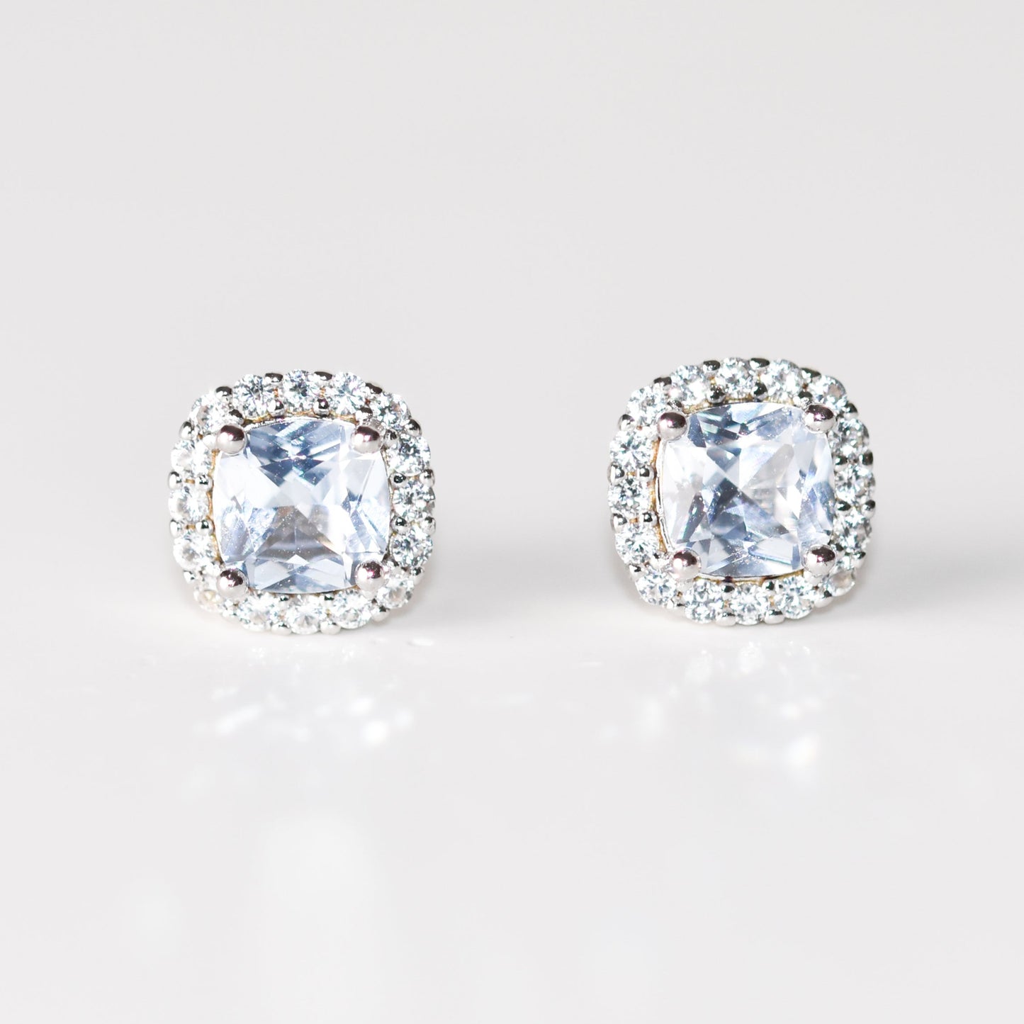Aretes tipo stud con aguamarina y halo de zafiros blancos creados en laboratorio